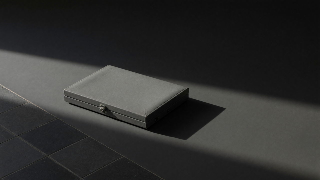 A closed metal strongbox on a dark floor, lit from one side.